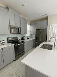uma cozinha com electrodomésticos de aço inoxidável e armários brancos em Villa, private pool, water park, Orlando parks em Kissimmee