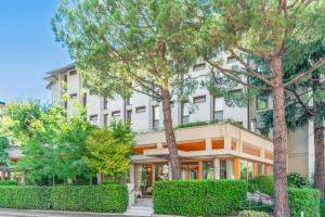 un edificio bianco con alberi di fronte di Albergo Sorriso a Boario Terme