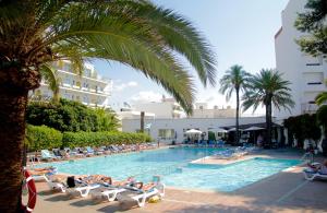 uma grande piscina com pessoas deitadas em espreguiçadeiras em Hotel Tropical em San Antonio