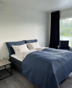 a bedroom with a bed with a blue comforter and a window at Senja Living in Stonglandseidet