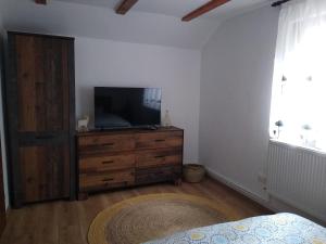 a bedroom with a television and a dresser with a bed at New and comfortable two bedroom house in Gărâna