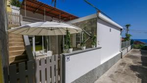 a white house with a fence and an umbrella at Little Townsuite Funchal in Funchal