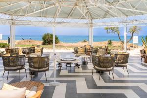 a patio area with chairs, tables, chairs and umbrellas at Grand Palladium Sicilia Resort & Spa in Campofelice di Roccella