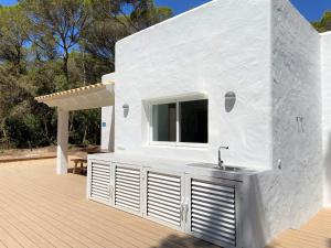 a white house with a sink on a deck at Can Valonsadero, Villa con Piscina in Es Calo