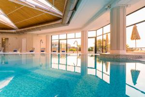 una piscina en un hotel con ventanas de cristal en Grand Palladium Sicilia Resort & Spa en Campofelice di Roccella