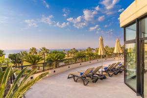 a row of lounge chairs and umbrellas on a balcony at Grand Palladium Sicilia Resort & Spa in Campofelice di Roccella