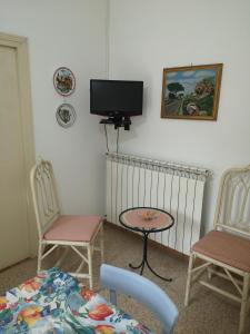 Zimmer mit 2 Stühlen und einem TV an der Wand in der Unterkunft Villa Florida in Fiuggi
