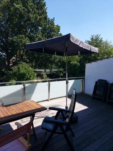 an umbrella sitting on a deck with a table and a chair at GästeHaus in Pinneberg