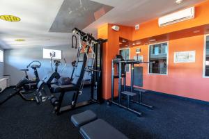 a gym with cardio equipment in a room with orange walls at Avalon Hotel & Conferences in Rīga