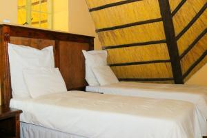 two beds sitting next to each other in a room at Mapelepele Cottage in Simunye