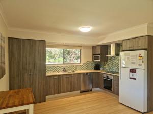 een keuken met houten kasten en een witte koelkast bij At Melaleuca 3 in Point Lookout