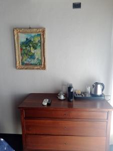 uma cómoda de madeira num quarto com uma pintura na parede em Locanda del Glicine em Campagnatico