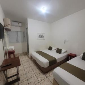 a hotel room with two beds and a desk and a television at Hotel Dona Lú in Sao Paulo