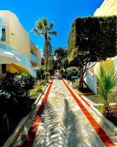 a red brick road with a palm tree and buildings at Mediterranea Apartments in Kato Daratso
