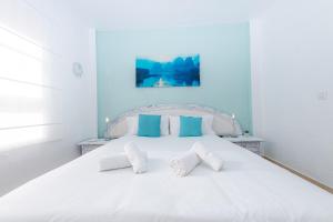 a bedroom with a white bed with blue walls at La sonada bright penthouse with views in Callao Salvaje