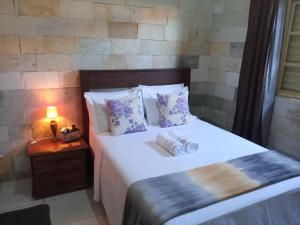 Un dormitorio con una cama blanca con almohadas y una mesa en Casa de Pedra, en Pirenópolis