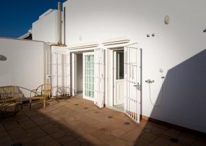 Cette chambre dispose de murs blancs, d'une porte et de chaises. dans l'établissement Ático con terraza Centro Ciudad, à El Puerto de Santa María 14 autres photos