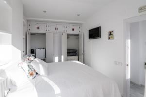 a white bedroom with a white bed with white cabinets at Ático con terraza Centro Ciudad in El Puerto de Santa María