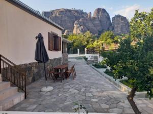 a patio with a table and an umbrella with mountains in the background at Paradise of Meteora B in Kastrákion