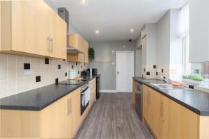 uma grande cozinha com armários de madeira e bancadas pretas em Ashton Mews apartment with free parking em Saint Annes on the Sea