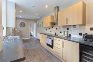uma cozinha com armários de madeira e um balcão preto em Ashton Mews apartment with free parking em Saint Annes on the Sea