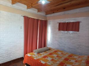 1 dormitorio con cama y cortina roja en Cabañas Ismiango "Agua de los pajaritos" en Collagasta