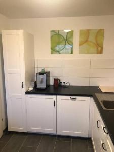uma cozinha com armários brancos e um balcão preto em Relax am Bodensee em Friedrichshafen