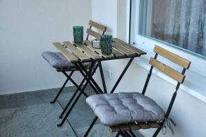 mesa de madera con 2 sillas y mesa con ventana en Guest House Atena en Nova Pazova