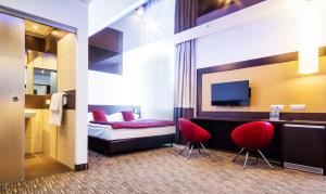 Habitación de hotel con 1 cama y 2 sillas rojas en Park Hotel Diament Zabrze - Gliwice, en Zabrze