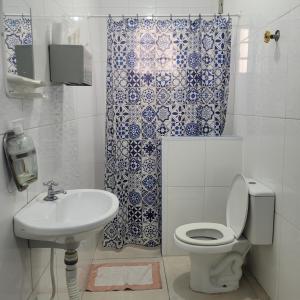 a bathroom with a toilet sink and a shower curtain at Hotel Dona Lú in Sao Paulo