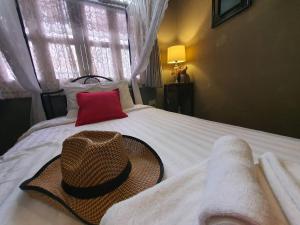 a hat sitting on top of a white bed at The Unforgotten B&B in Bangkok