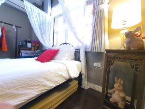 a bedroom with a bed and a window with a stuffed rabbit at The Unforgotten B&B in Bangkok