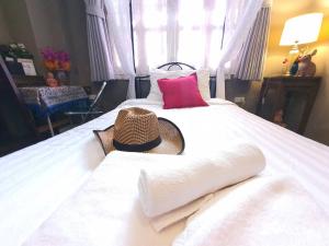 1 dormitorio con 1 cama con sombrero en The Unforgotten B&B, en Bangkok