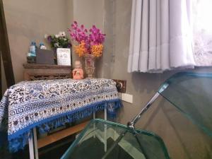 a doll sitting on a table in a room with flowers at The Unforgotten B&B in Bangkok
