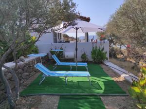 a patio with two lounge chairs and an umbrella at ''Koukmos beach'' Greenspace Living - Private sandy beach in Parákoila