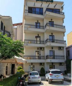 two cars parked in front of a tall building at Lucic Rooms & Suites in Budva