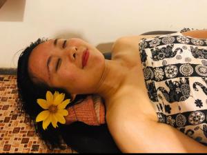 Una mujer acostada en una cama con una flor en la boca en Ariya Rest & Ayurveda spa, en Polonnaruwa