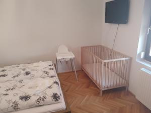 a room with a crib and a table and a tv at Tánczos Vendégház in Balatonalmádi