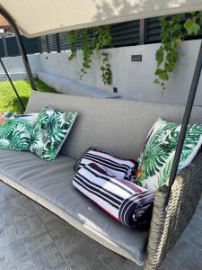 a wicker rattan couch with pillows on a patio at HelaMoni, New 5 Star 2 Person apartments with pool in Malinska
