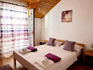 a bedroom with a large white bed with purple pillows at Apartments Sponga in Polače