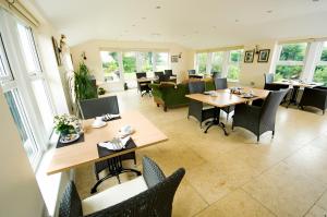 a dining room with tables and chairs and windows at Graysonside in Cockermouth