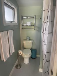 a bathroom with a toilet and a window and towels at Gallagher’s Travels Bar Harbor Motel and Cottages in Bar Harbor