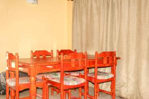 a dining room table with four chairs and a wooden table at Mapelepele Cottage in Simunye