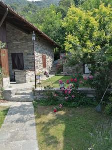 uma casa de pedra com um quintal com flores em Chalet di Montagna em San Giuliano