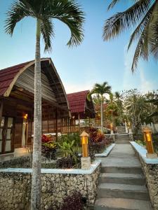 a resort with a palm tree and a building at Griyatama Bungalow in Nusa Penida