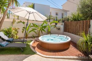 a hot tub in a garden with a chair and an umbrella at L'Oursinade - Jolie maison avec Jacuzzi et jardin in Bandol