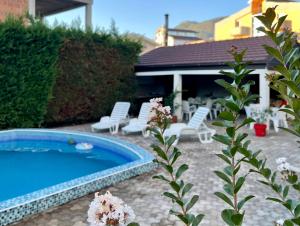 einen Pool im Garten mit weißen Stühlen und Blumen in der Unterkunft 3 Bedroom Apartment with pool in Čeluga