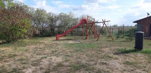 a playground with a red slide in a yard at Akácvirág Vendégház in Ács
