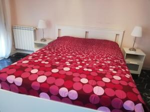 ein rotes Bett mit rosa und weißen Polka-Punkten-Bettwäsche in der Unterkunft Casa Tevere in Syrakus