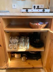 a cupboard with glasses and a basket on top at Zem Priedēm in Lapmežciems